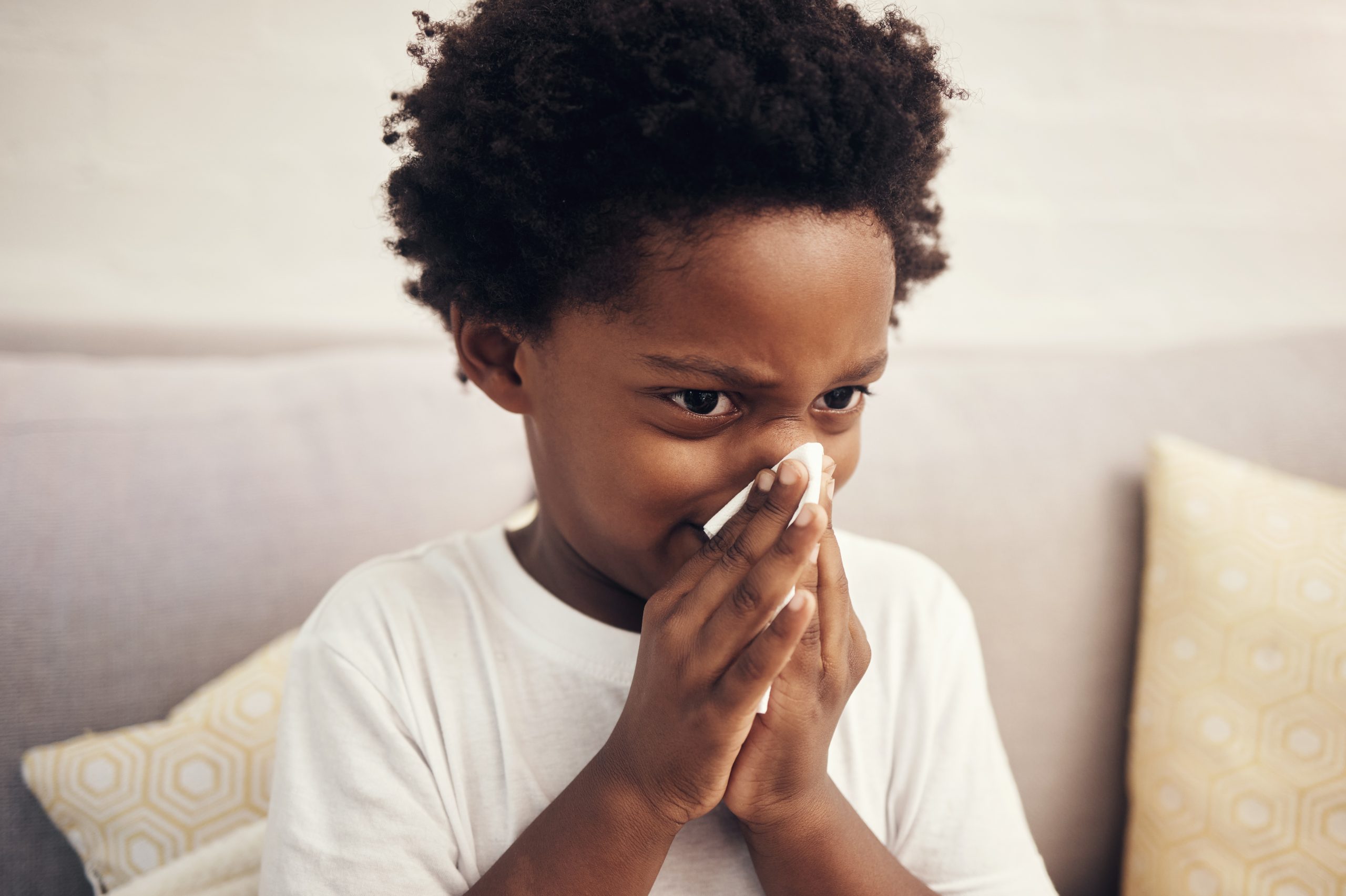 Sick child blowing his nose into a tissue